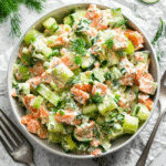 Tasty-style overhead shot of creamy salmon cucumber salad in a white bowl with dill and cucumber