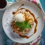 Tasty-style top-down photo of an apple pie biscuit topped with vanilla ice cream and caramel drizzle, served with chai tea.