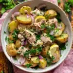Overhead view of tuna potato salad with parsley, capers, and lemon vinaigrette in a ceramic bowl